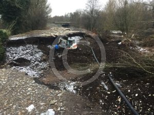 A lone digger and three workmen make repairs
