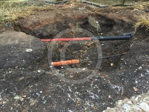 Exposed electricity cables stretched between remaining earth mounds